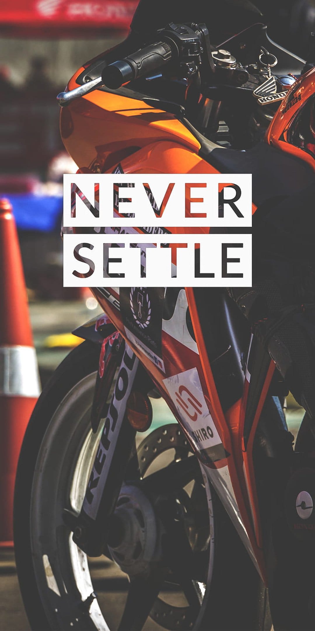 Orange racing sportbike with Never Settle typography displayed on a detailed mechanical close-up background.