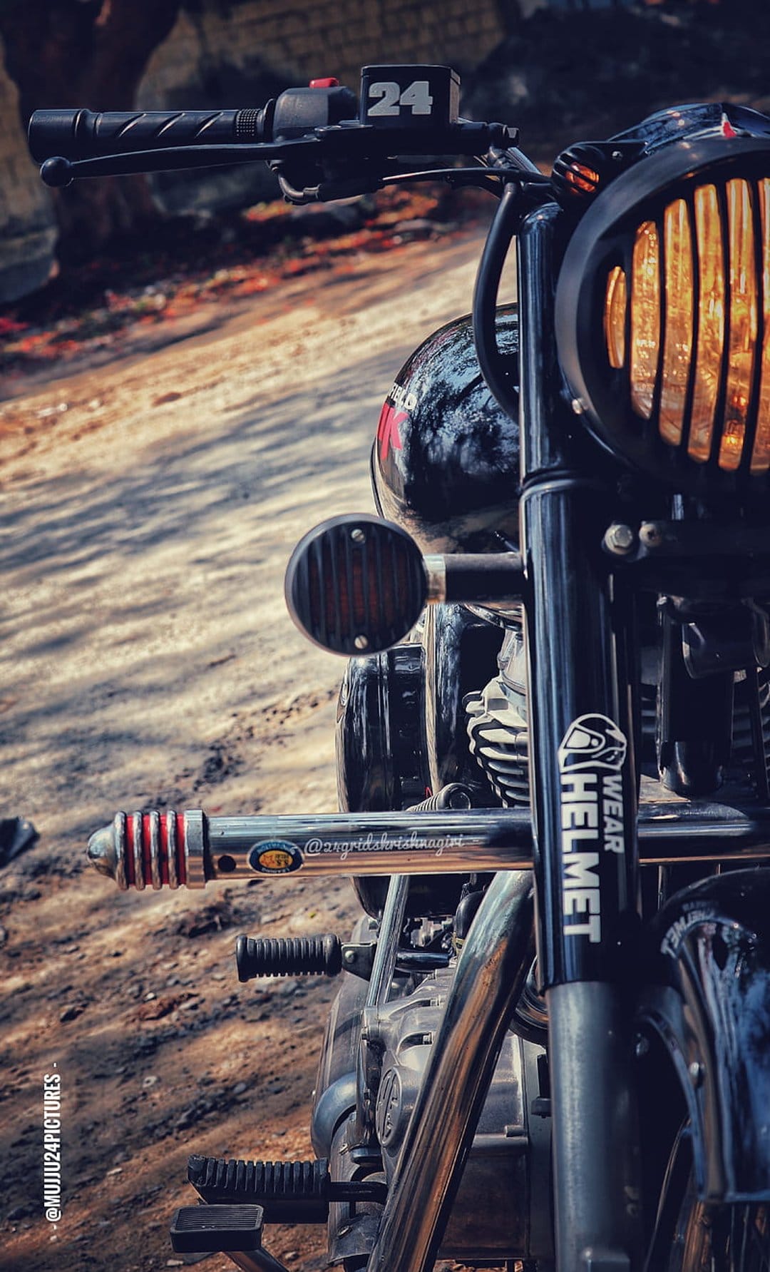 Royal Enfield motorcycle with a black headlamp grille, chrome crash guard, and digital display on a dirt road.
