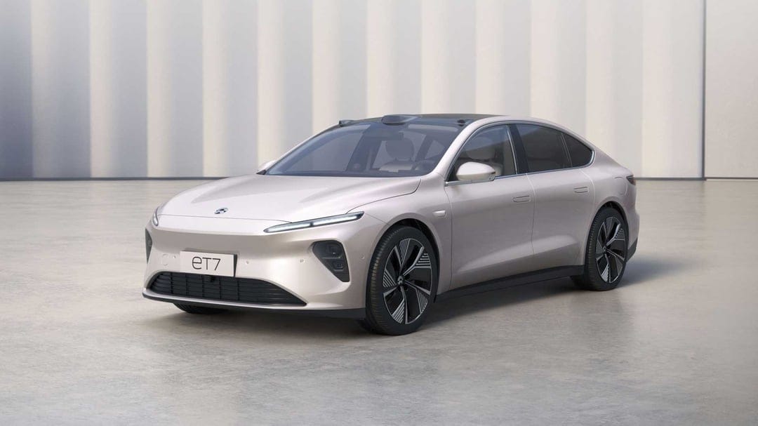 Champagne NIO ET7 electric sedan in a white studio with soft lighting and a minimalist ribbed background.