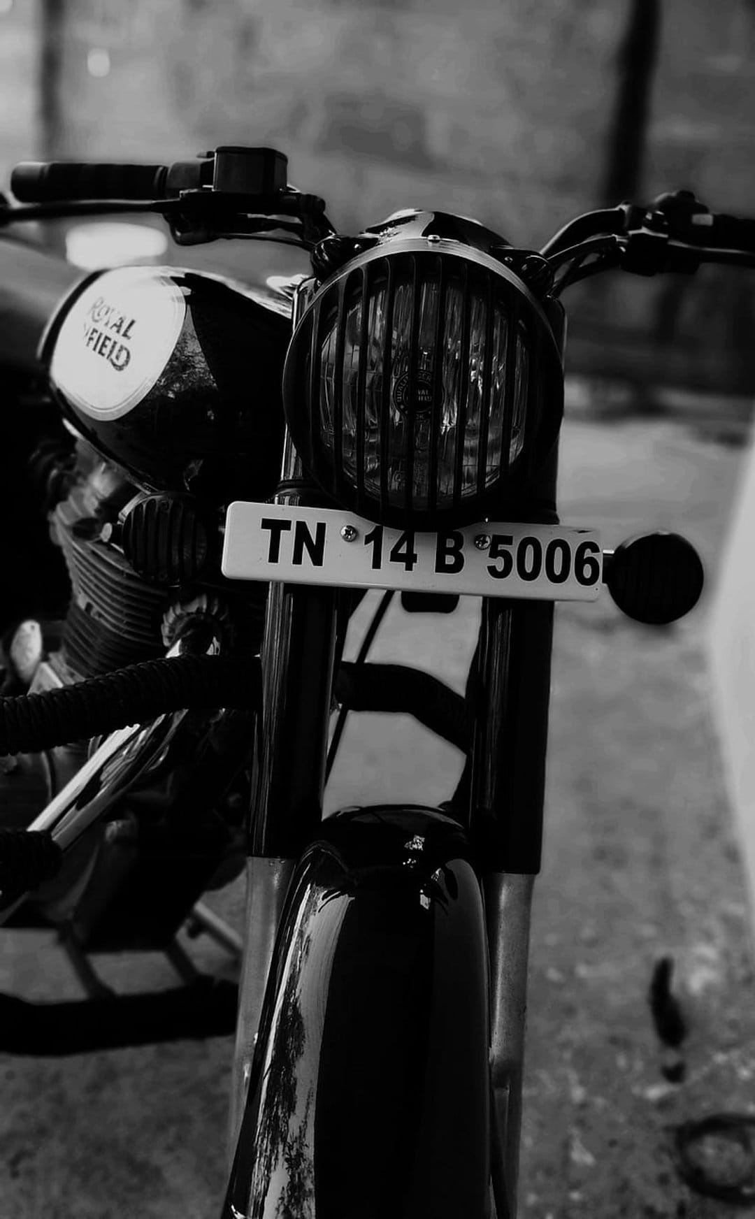 Royal Enfield vintage motorcycle front with a circular headlamp and license plate in high-contrast black and white.
