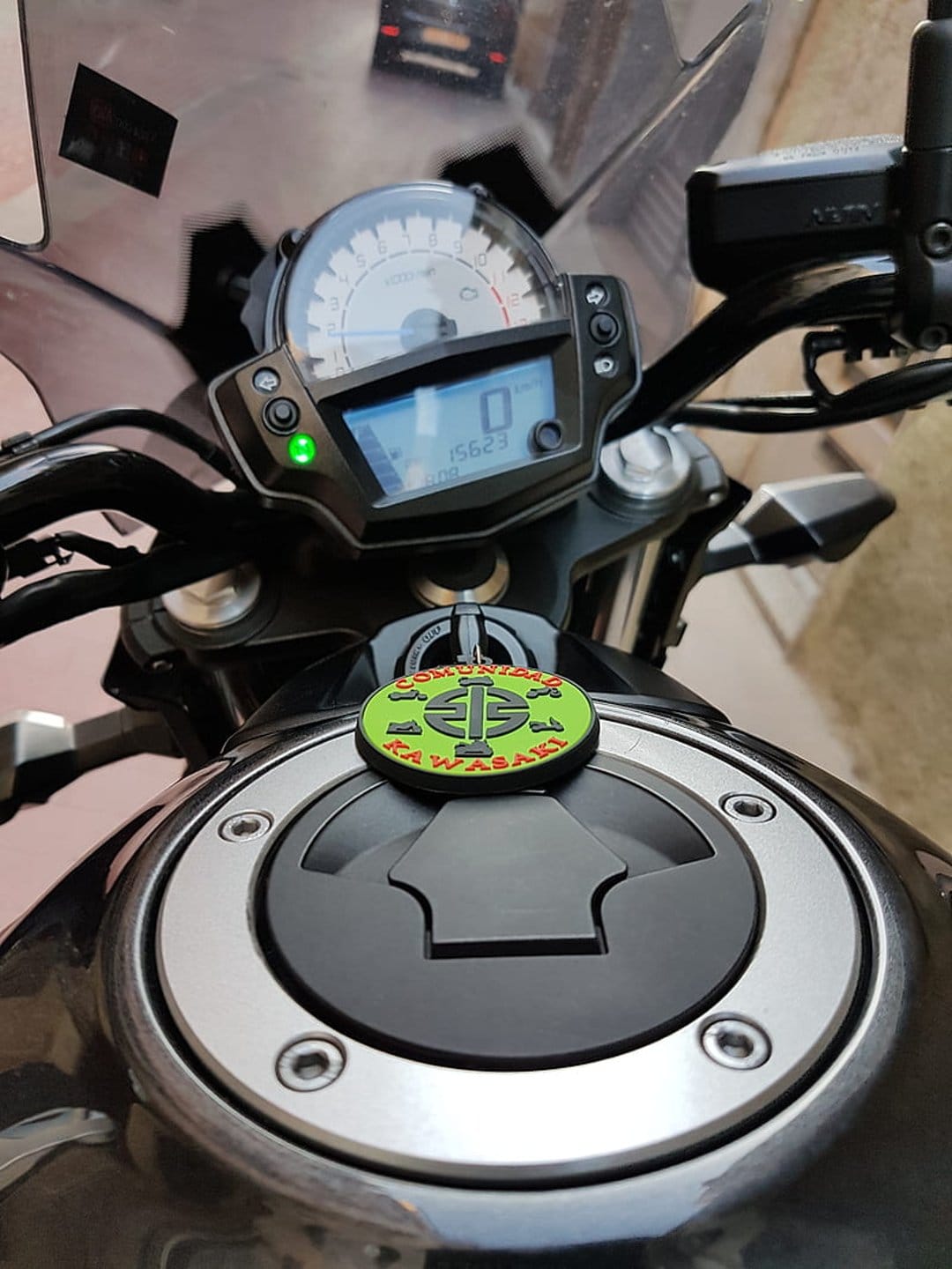 Kawasaki motorcycle dashboard with a glowing digital speedometer next to a black fuel tank and green emblem.