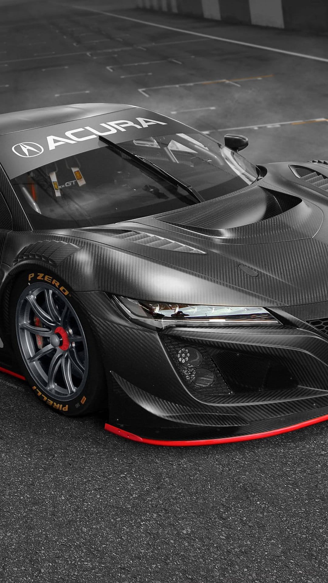 Acura NSX GT race car with a visible carbon fiber body and red accents parked on a textured asphalt race track.