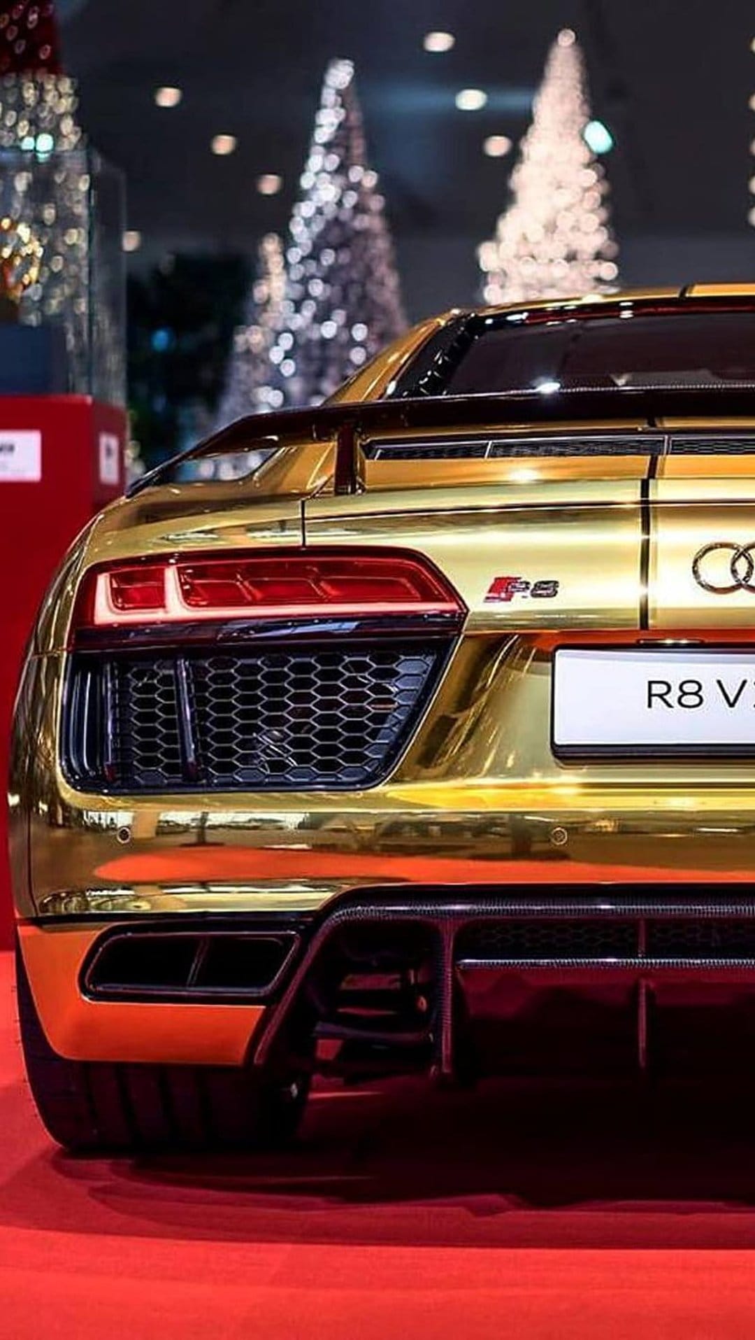 Golden Audi R8 V10 rear taillights and honeycomb grille with blurred Christmas trees and lights in the distance.