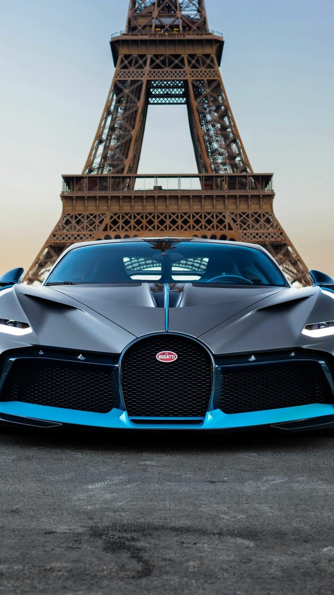 Front view of a matte grey Bugatti Divo with electric blue trim parked before the Eiffel Tower in Paris.