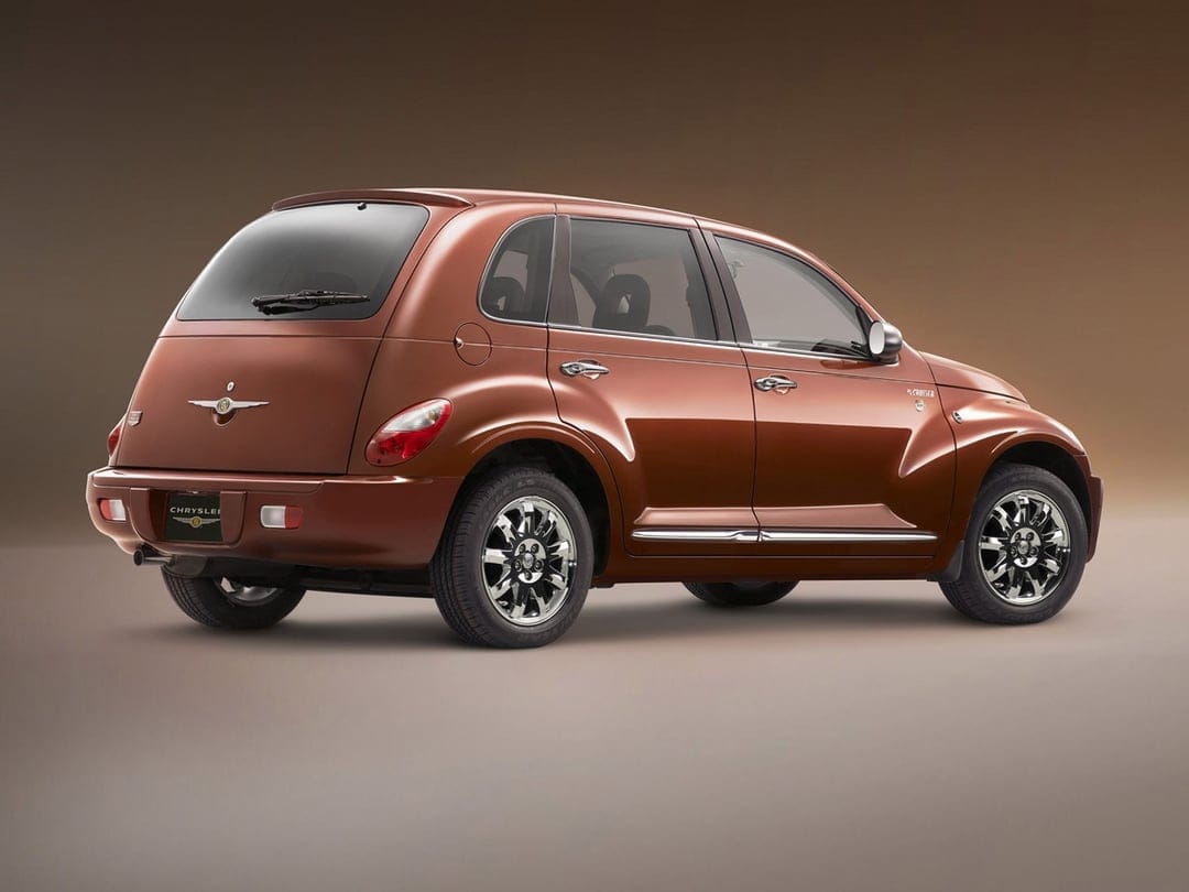 Copper Chrysler PT Cruiser viewed from the rear three-quarter angle in a studio with a warm brown background.