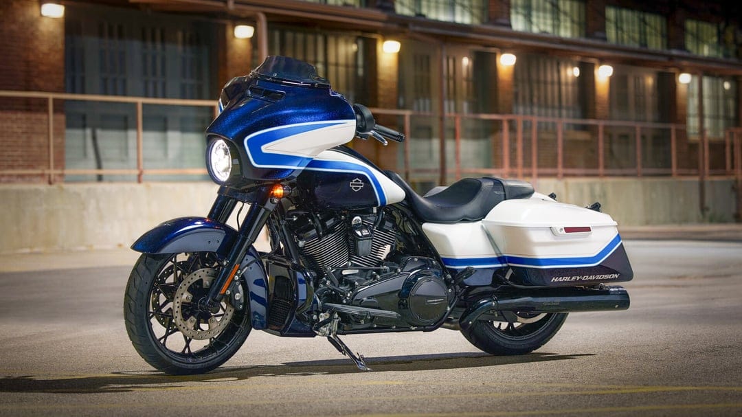Blue and white Harley-Davidson motorcycle parked in front of an industrial building with warm glowing lights