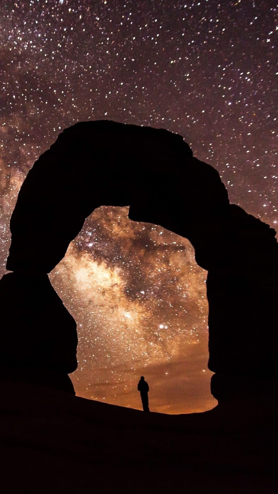Silhouetted person stands under a stone arch beneath a vibrant starry galaxy with purple and gold nebula clouds.