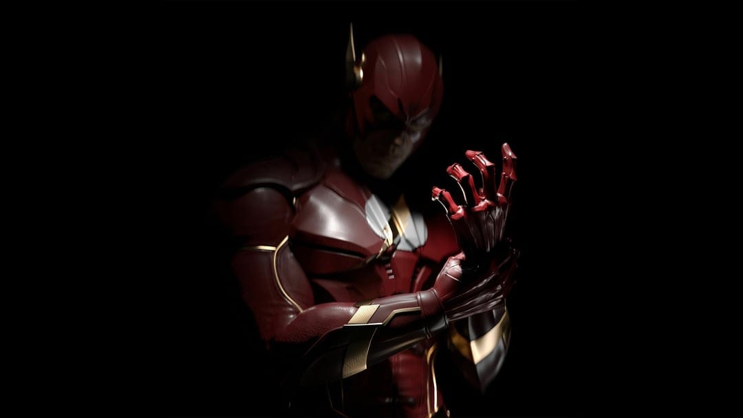 The Flash in red and gold armor adjusting his glove against a black background with dramatic low-key lighting.