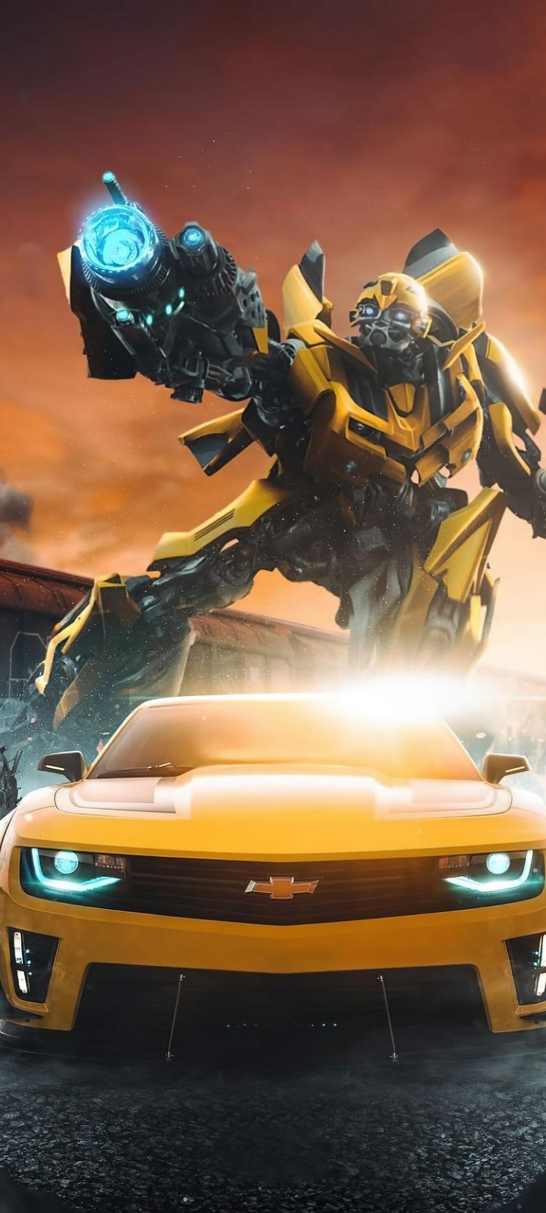 Bumblebee robot stands with a plasma cannon beside a yellow Camaro car against a burning orange sunset sky.