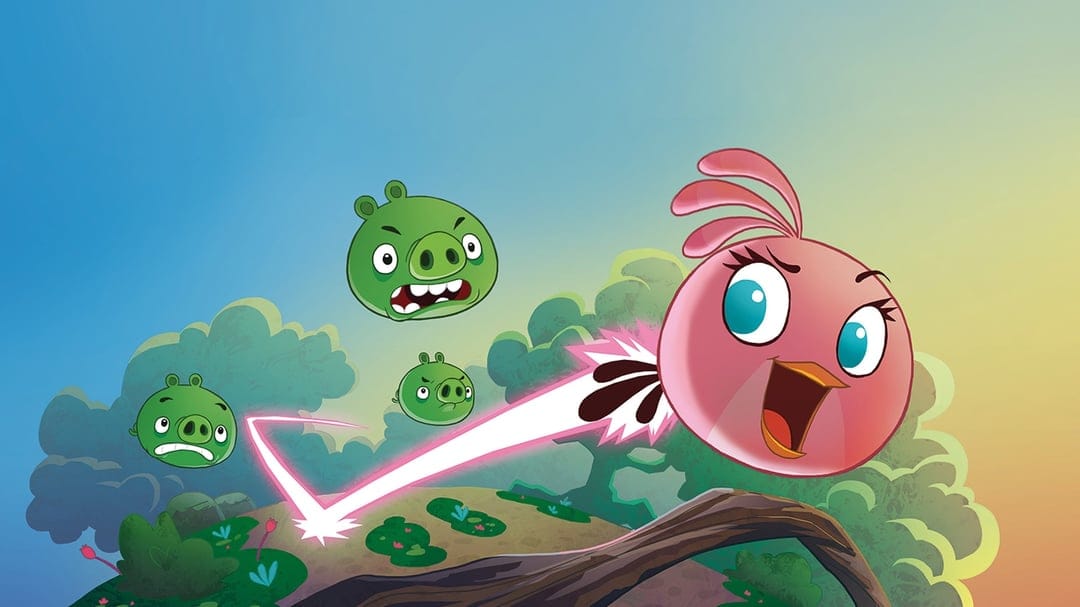 Pink bird Stella flies through a cartoon jungle with green pigs and a pink energy trail under a blue sky.
