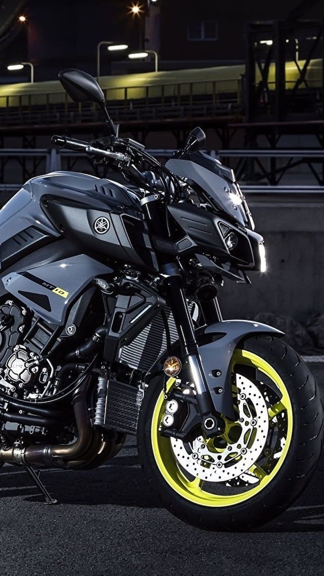Yamaha MT-10 motorcycle with glowing neon yellow wheels parked in a dark city street with blurred background lights.