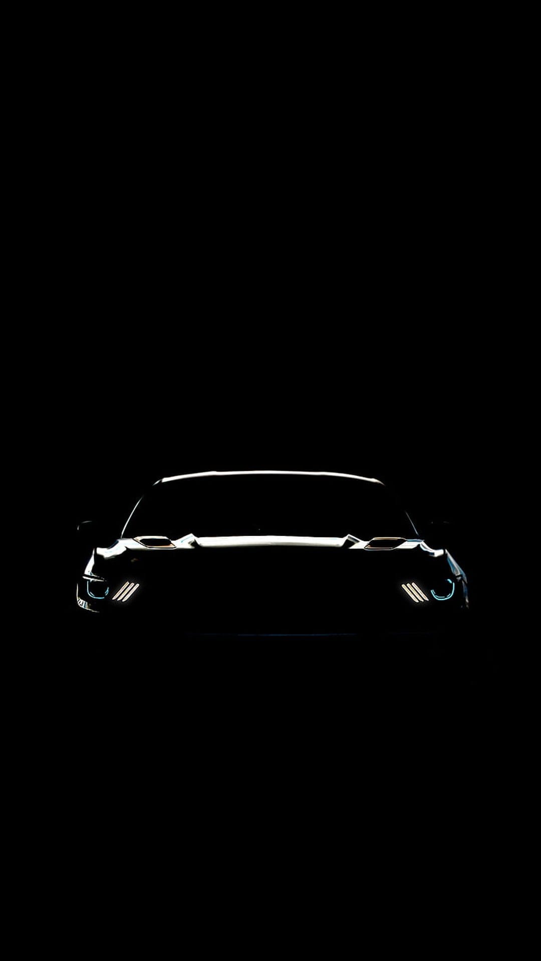 Ford Mustang LED headlights glow with triple-bar signature lights against a dark black silhouetted car front.