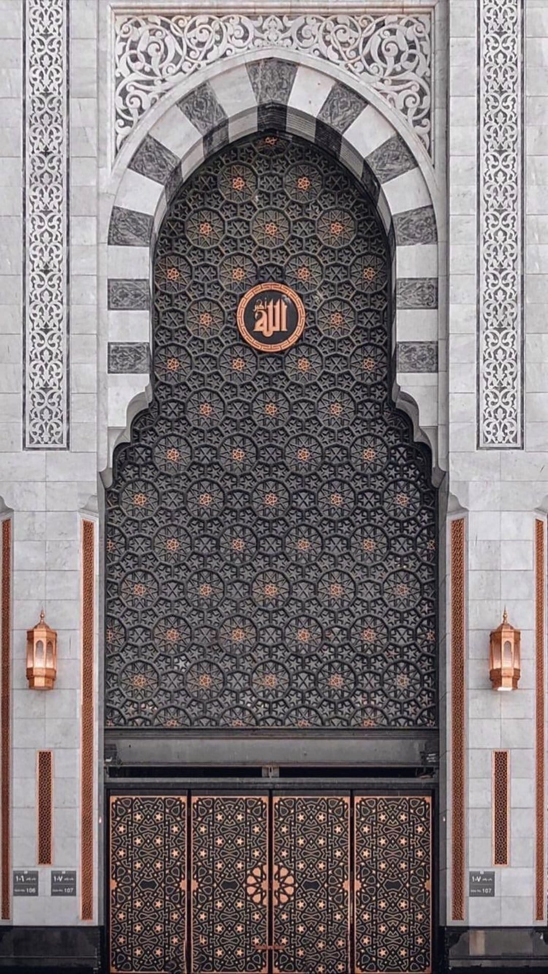 Circular Arabic calligraphy emblem centered on a marble archway with geometric patterns and hanging lanterns.