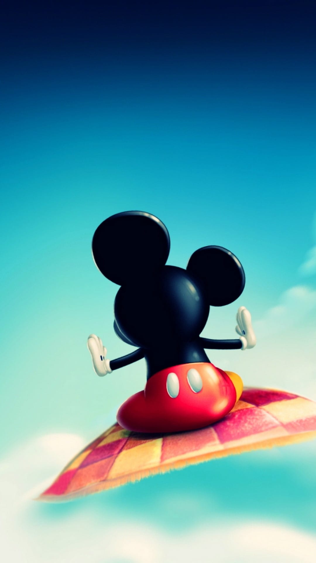 Mickey Mouse sits on a checkered magic carpet flying through a bright blue sky with soft white clouds.