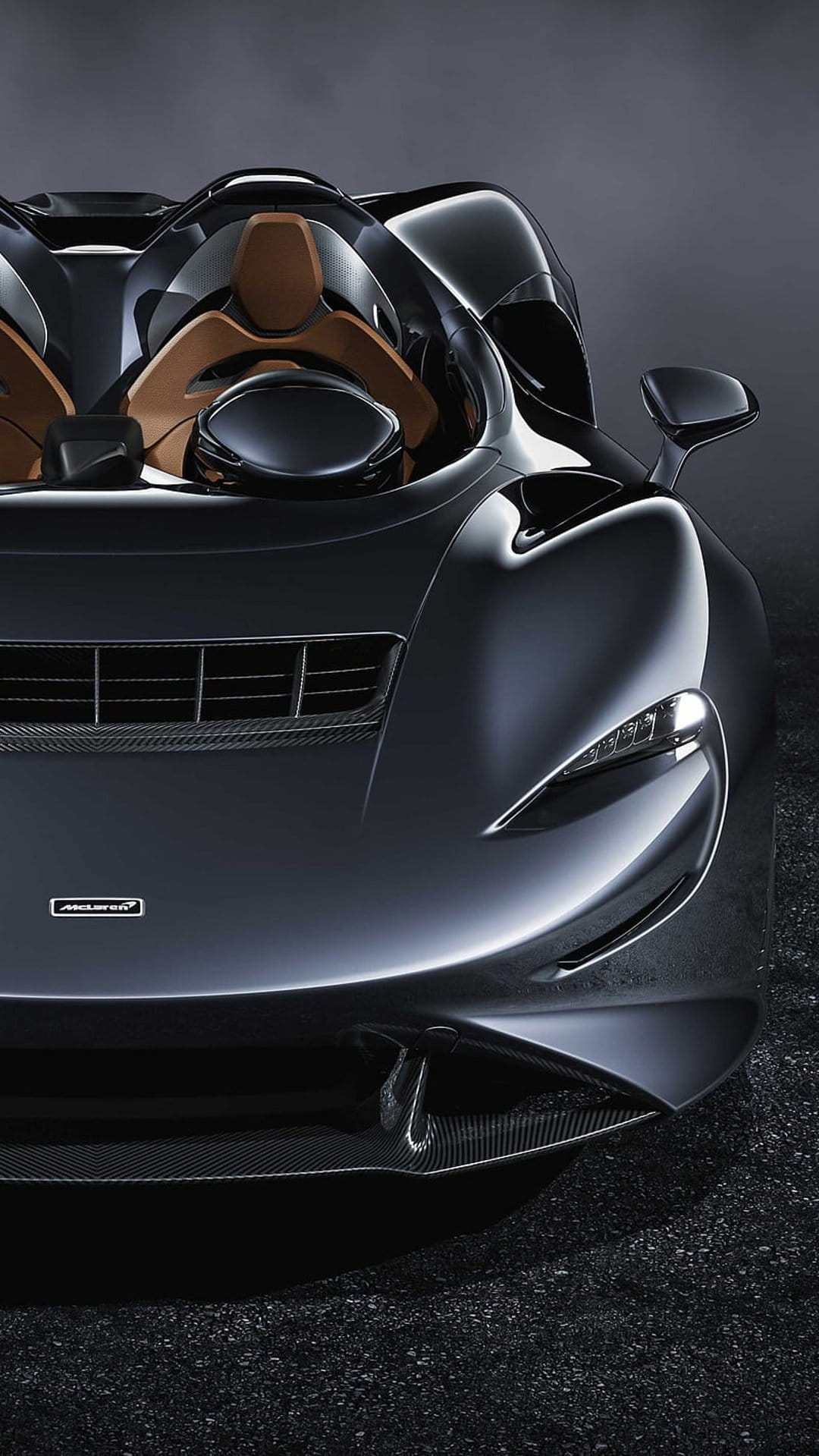 McLaren Elva supercar in dark gray with visible tan interior, low-angle front view, and carbon fiber details.