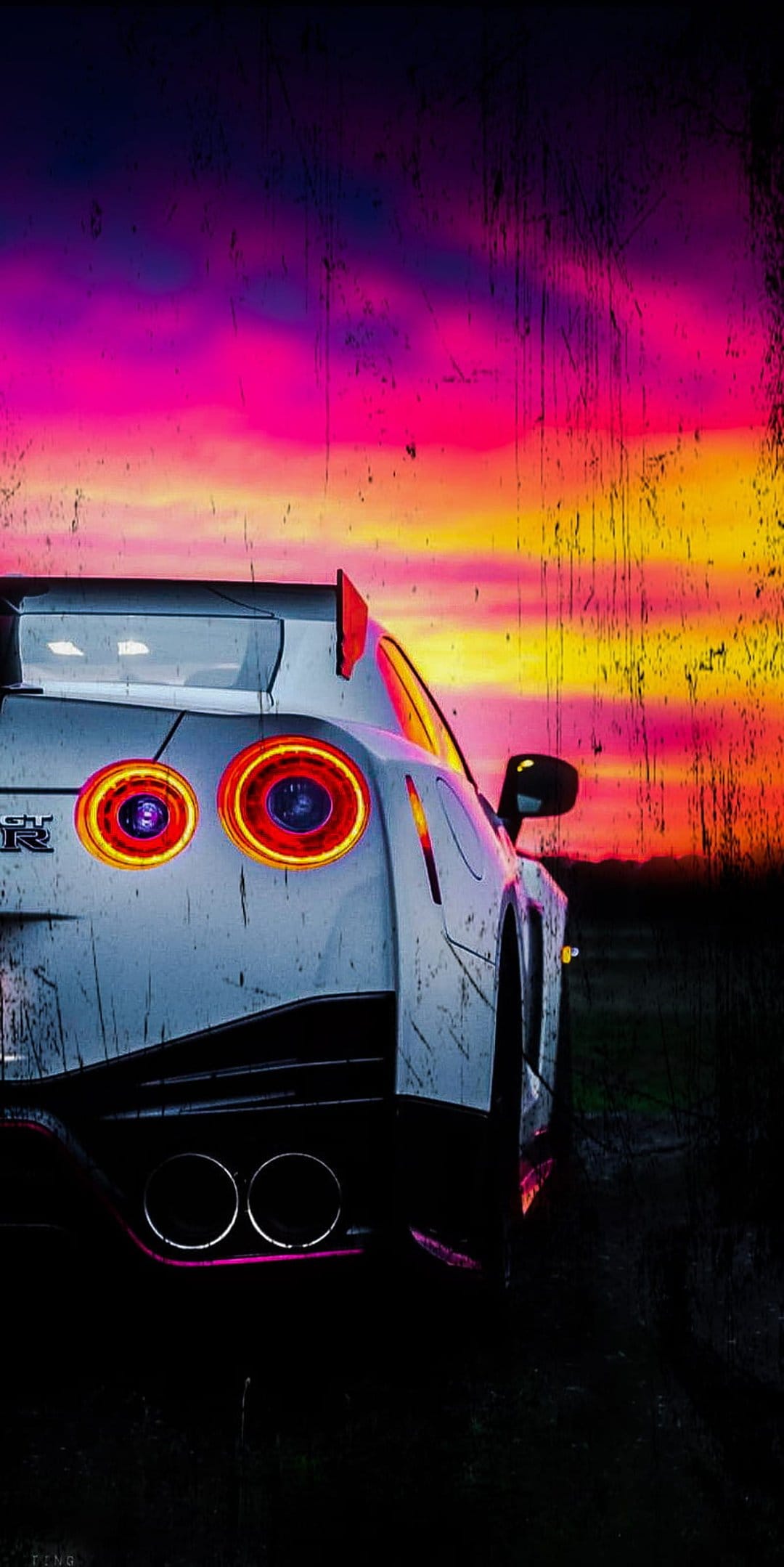 Nissan GT-R circular red taillights glow intensely against a textured sunset sky with purple and orange hues.