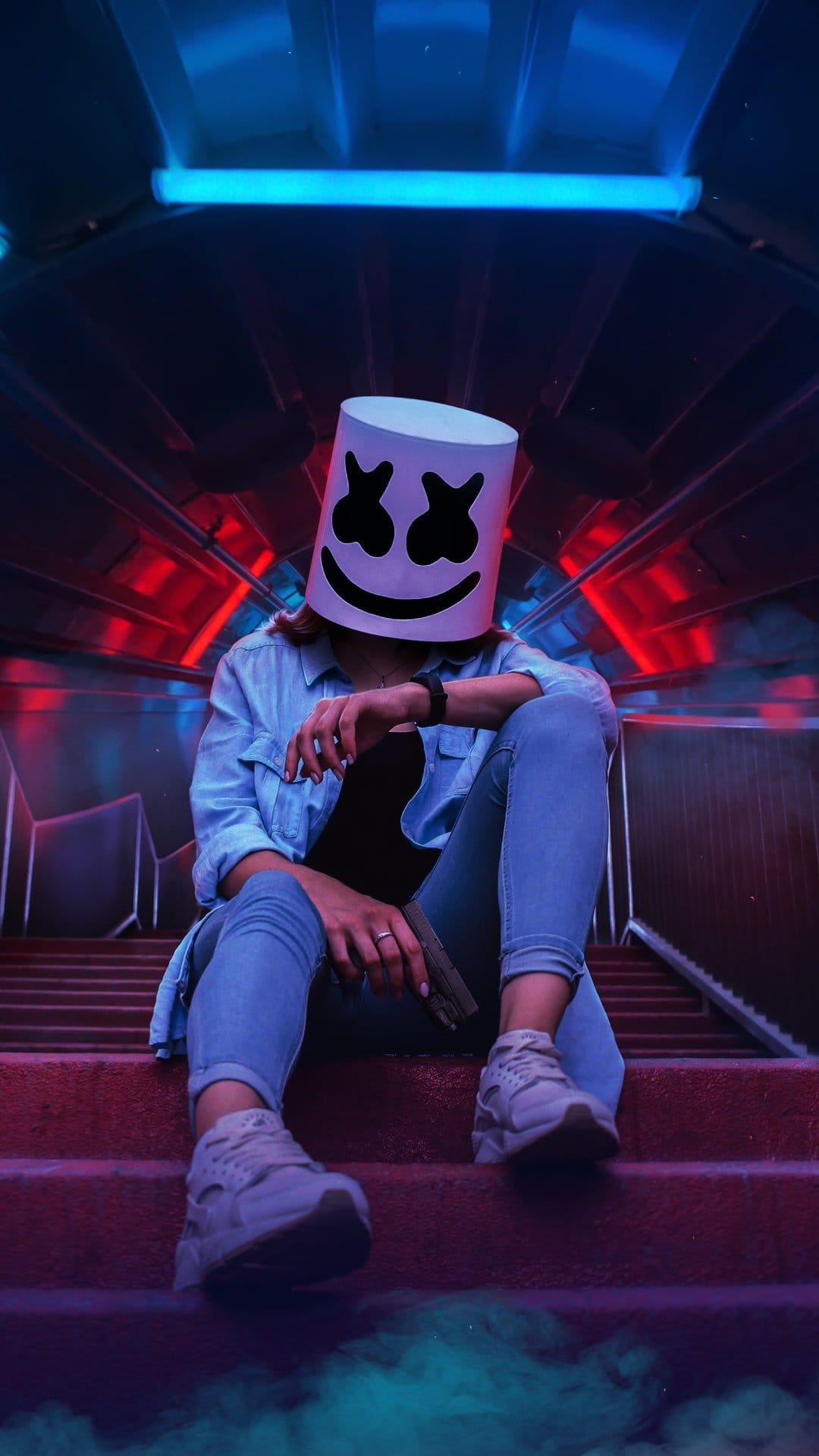 Masked person in a denim shirt sits on red stairs with blue neon lights and swirling atmospheric smoke.