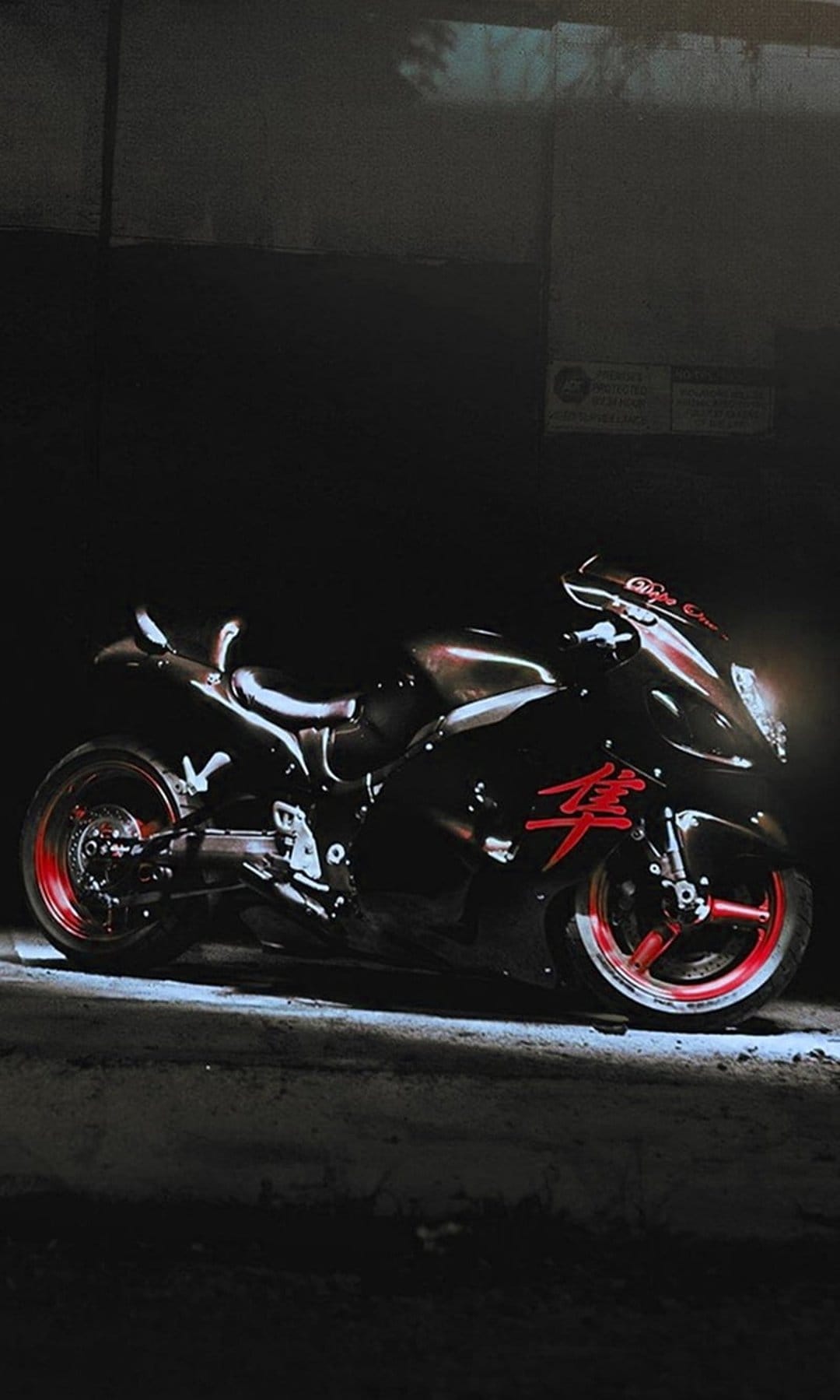 Suzuki Hayabusa motorcycle in matte black with red rim accents positioned in a dark, atmospheric setting.