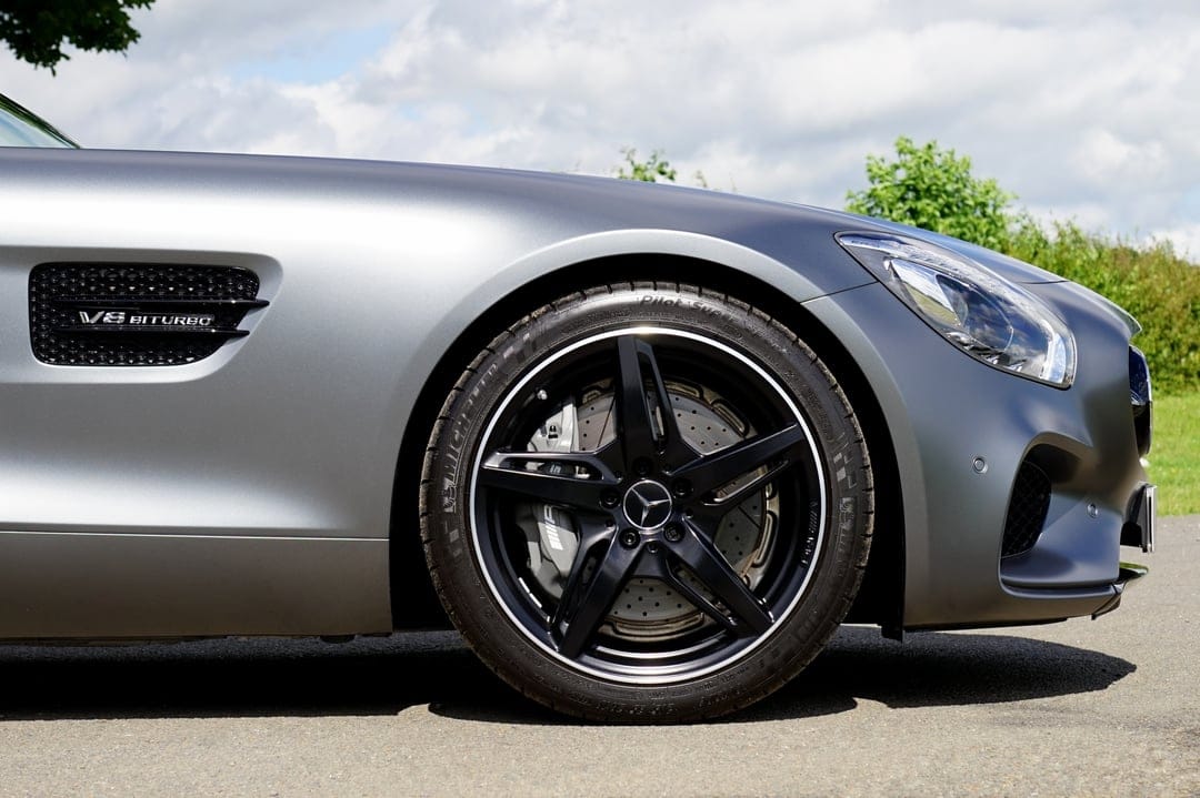 Mercedes-AMG GT R wheel and silver fender with a V8 Biturbo badge against a blurred greenery and sky background.