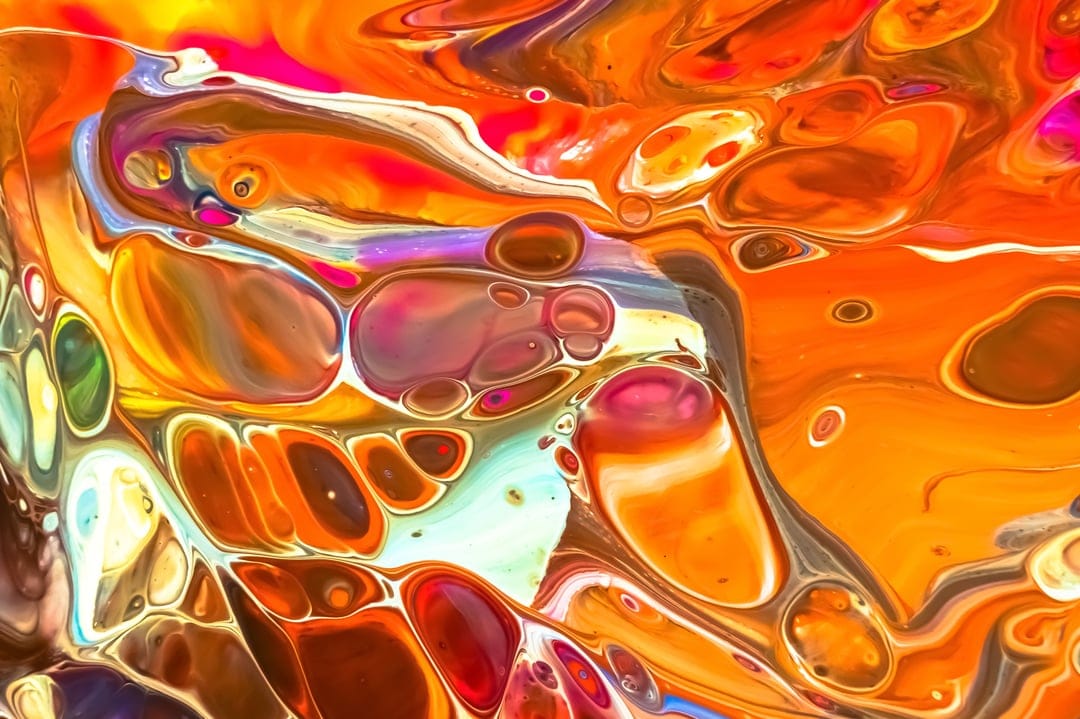Swirling orange and blue liquid paint forming organic cell patterns and marbled textures in a vertical frame.