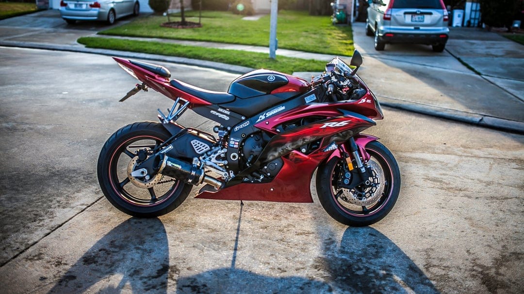 Custom red Yamaha R6 sportbike parked on a driveway with golden hour lighting and soft suburban background.