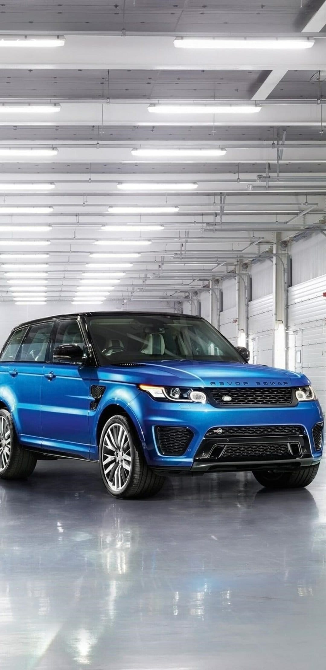 Blue Range Rover Sport SVR parked in a bright studio with overhead LED lights and reflective grey flooring.