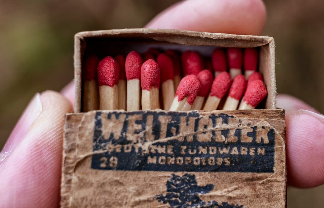Vintage German matches with red tips sit inside a weathered cardboard box with faded black typography.