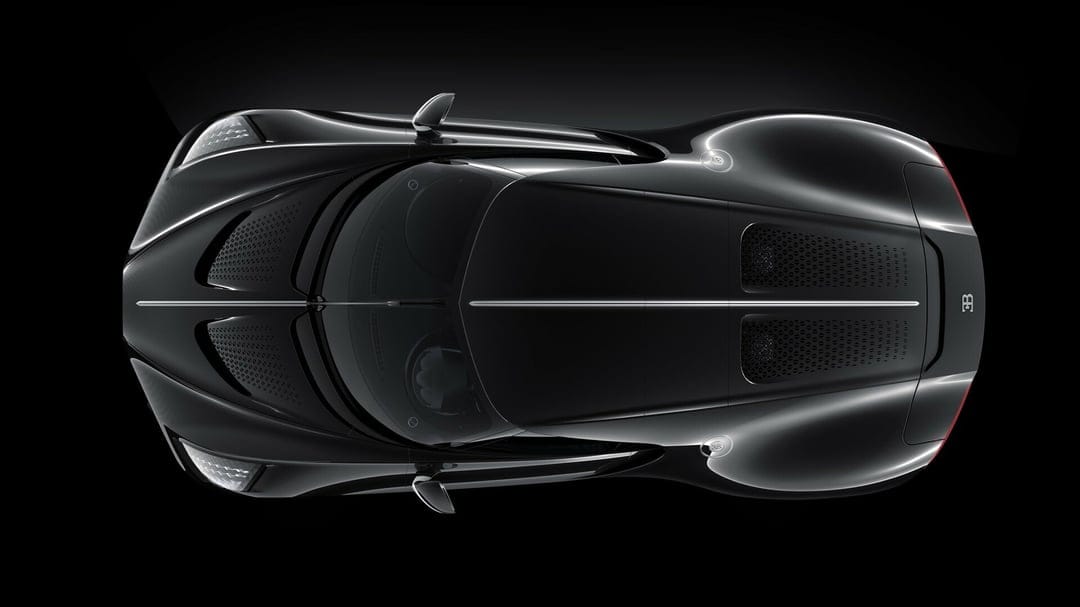 Top-down view of a black Bugatti hypercar with carbon fiber details and a chrome spine on a black background.