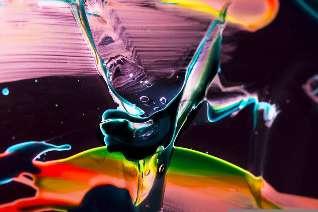 Neon green and orange paint swirls weave through dark liquid with reflective spherical bubbles and glossy textures.