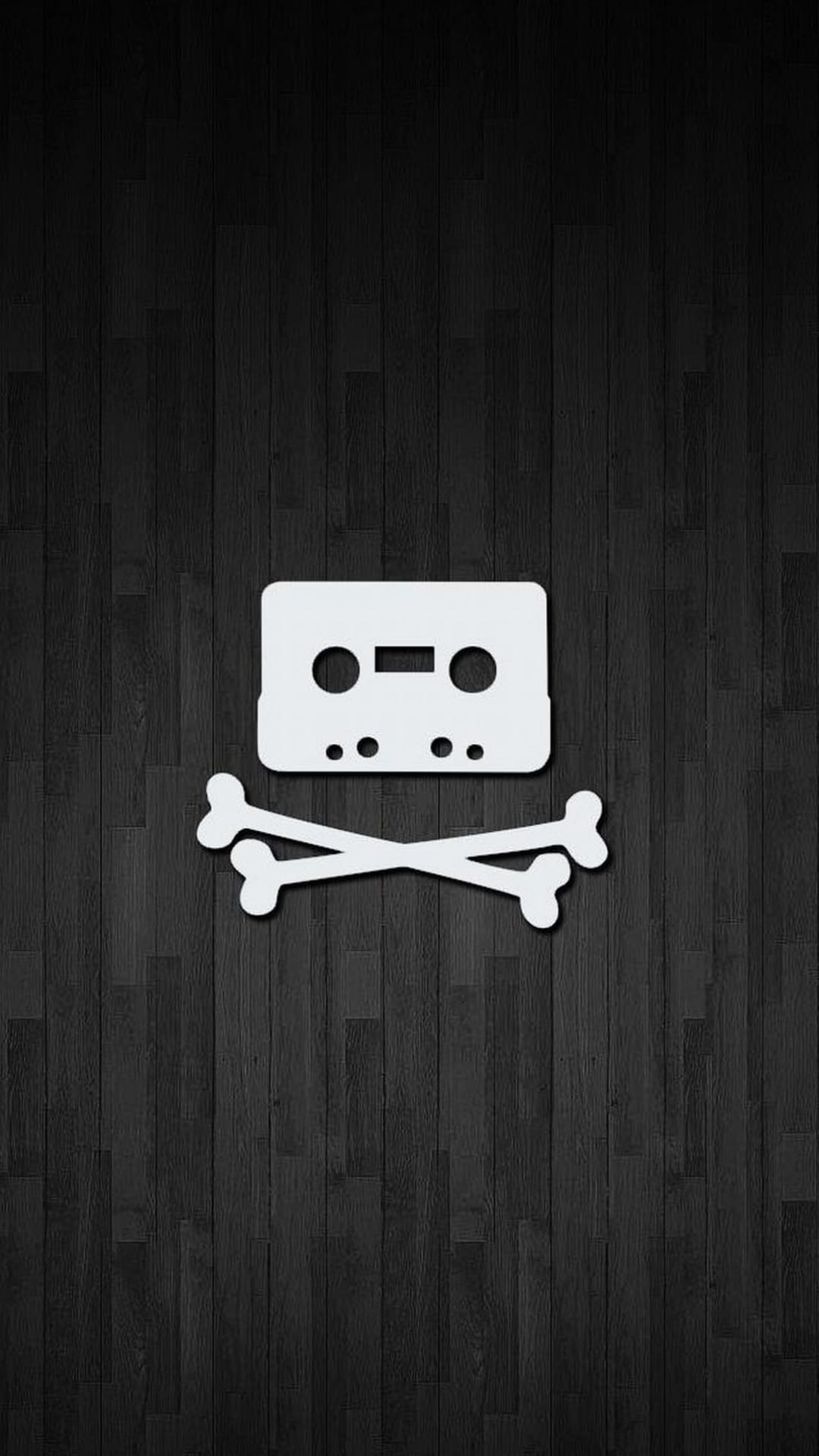 White cassette tape arranged over crossed bones centered on a textured vertical dark wood grain background.