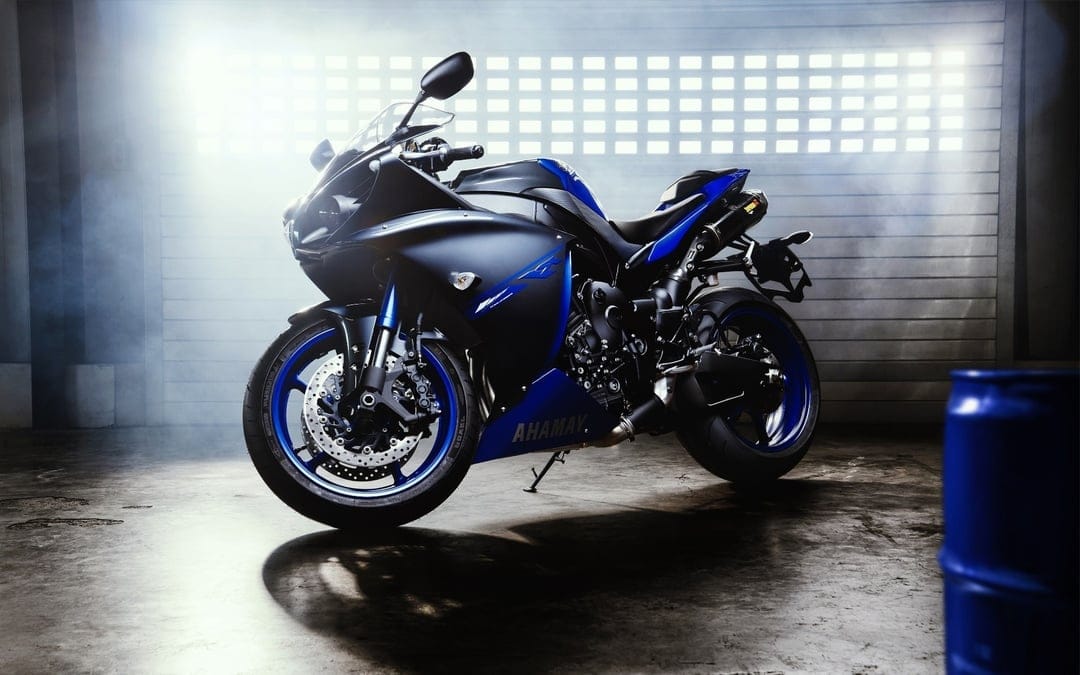 Blue and matte black Yamaha R1 sportbike in a misty industrial garage with dramatic backlighting and smoke.