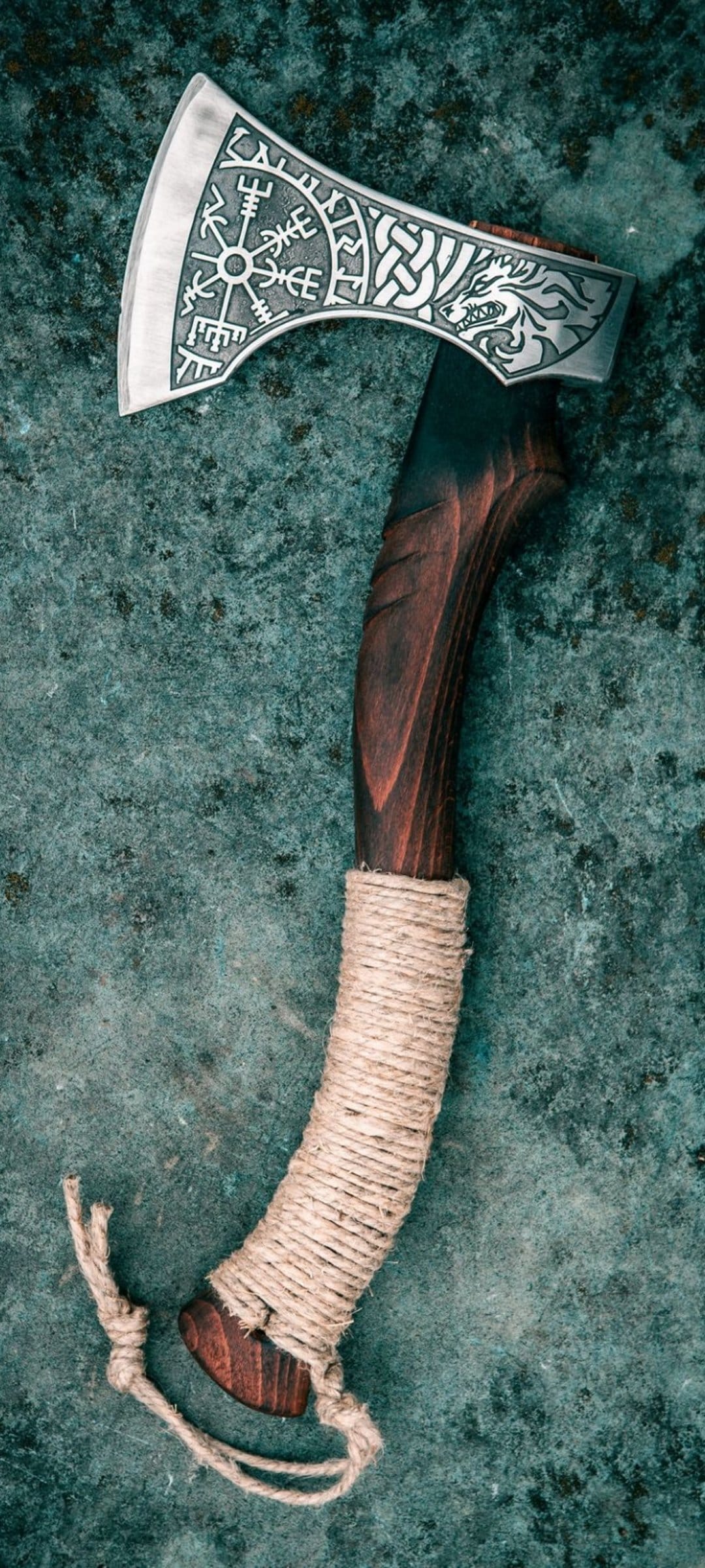 Viking axe featuring a wolf engraving and Vegvisir compass on its blade against a textured green background.