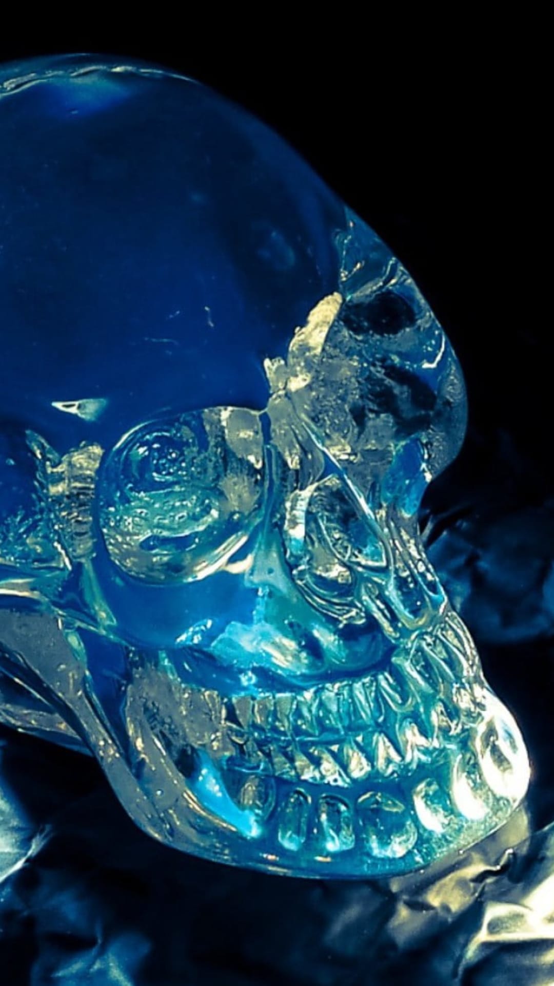 Translucent blue ice skull with sharp crystalline teeth and glowing light highlights against a black background.