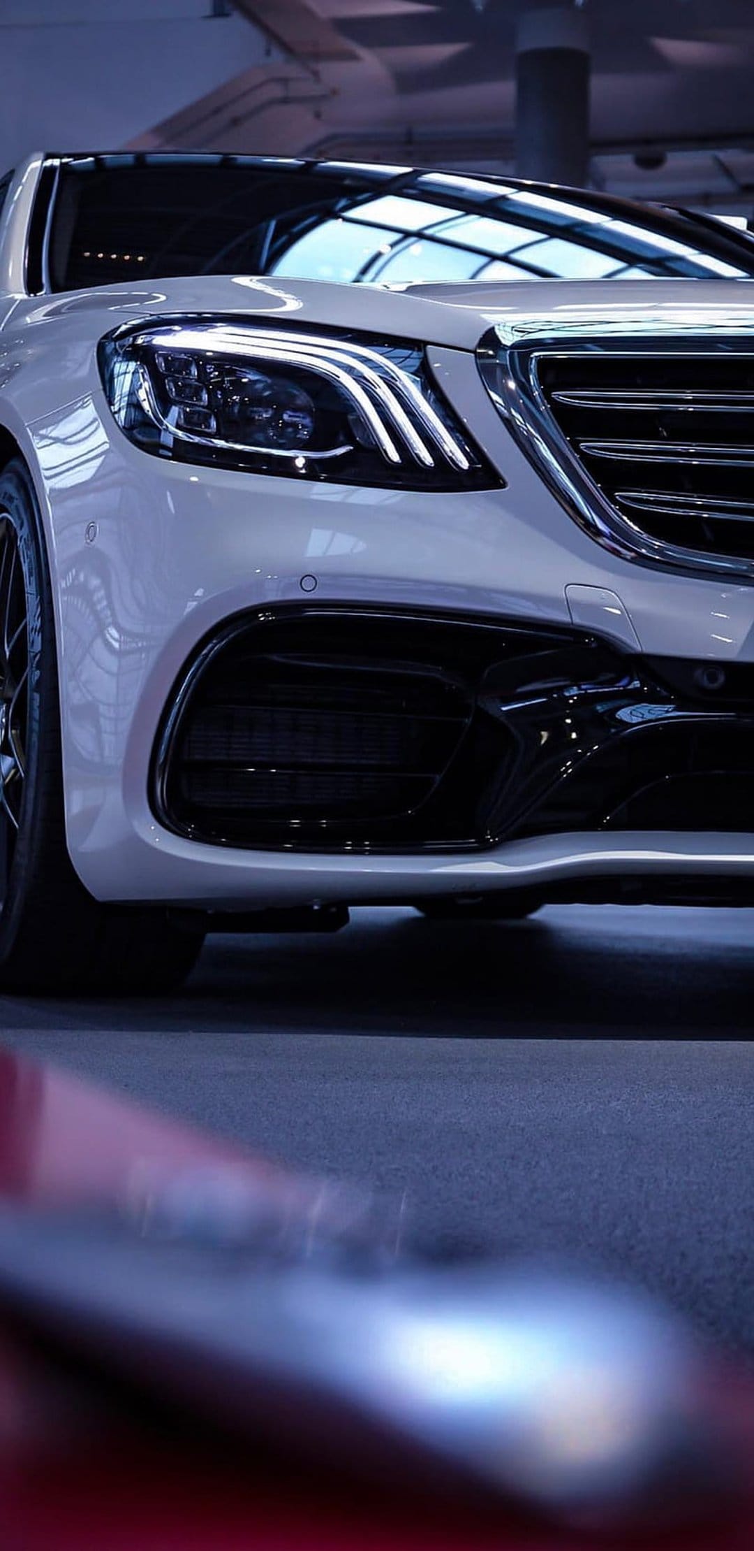 White luxury sedan front end featuring a chrome grille, sharp LED headlights, and aggressive lower air intakes.
