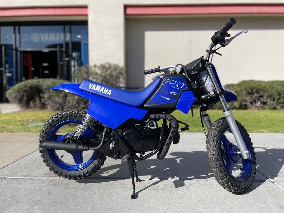 Blue Yamaha PW50 mini dirt bike parked on concrete with off-road tires and a matching blue seat and rims.