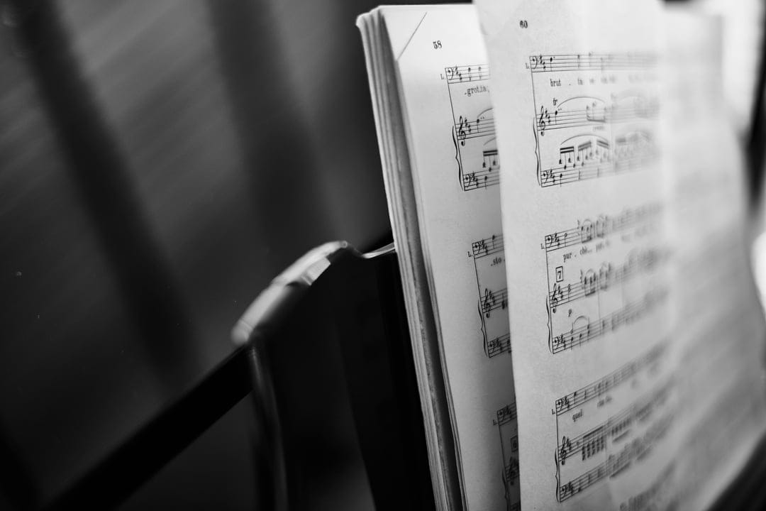 Sheet music with printed notes on a book stand featuring a shallow depth of field in black and white tones.