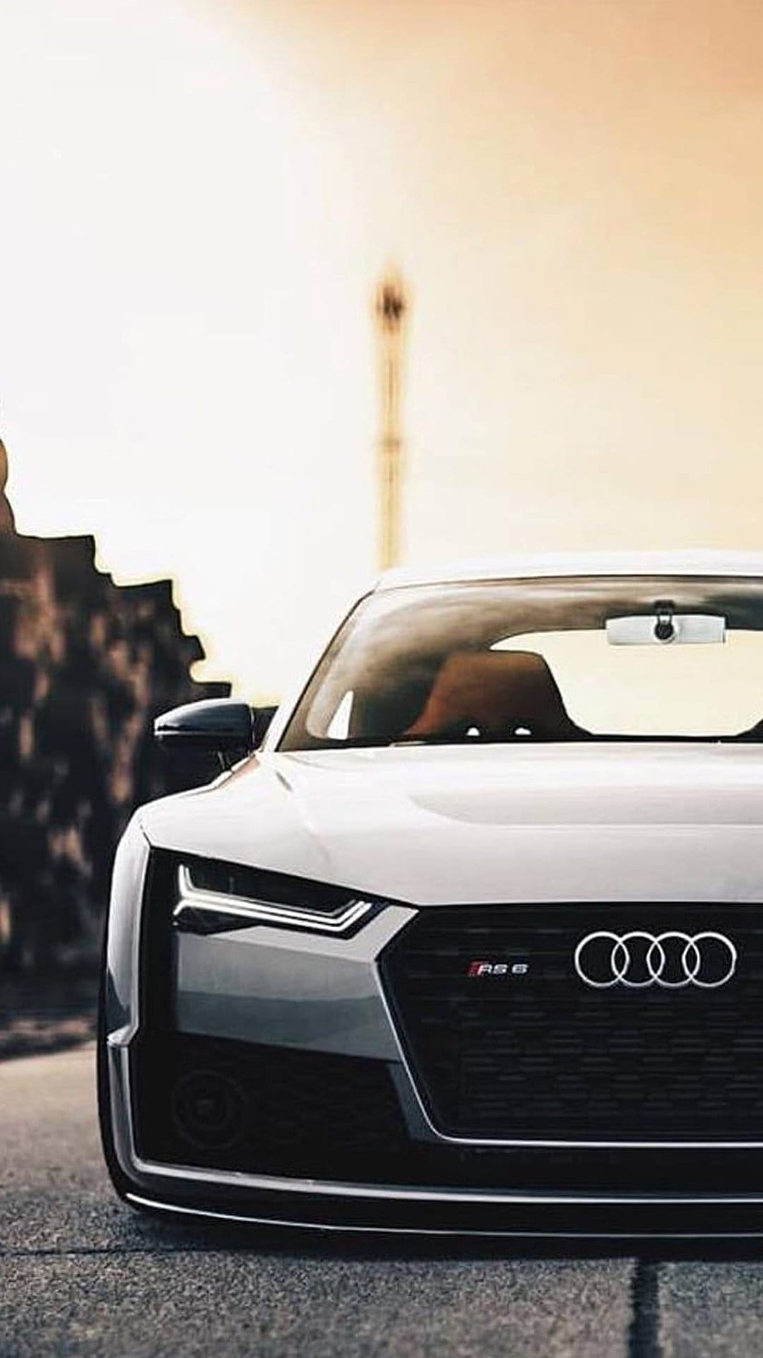 White Audi RS6 front grill and sharp LED headlights with the chrome four rings logo on a blurred background.
