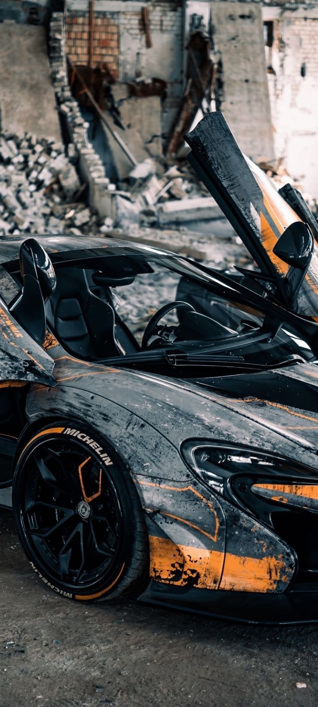 McLaren P1 with colorful graffiti paint and open doors parked inside a crumbling, debris-filled brick building.