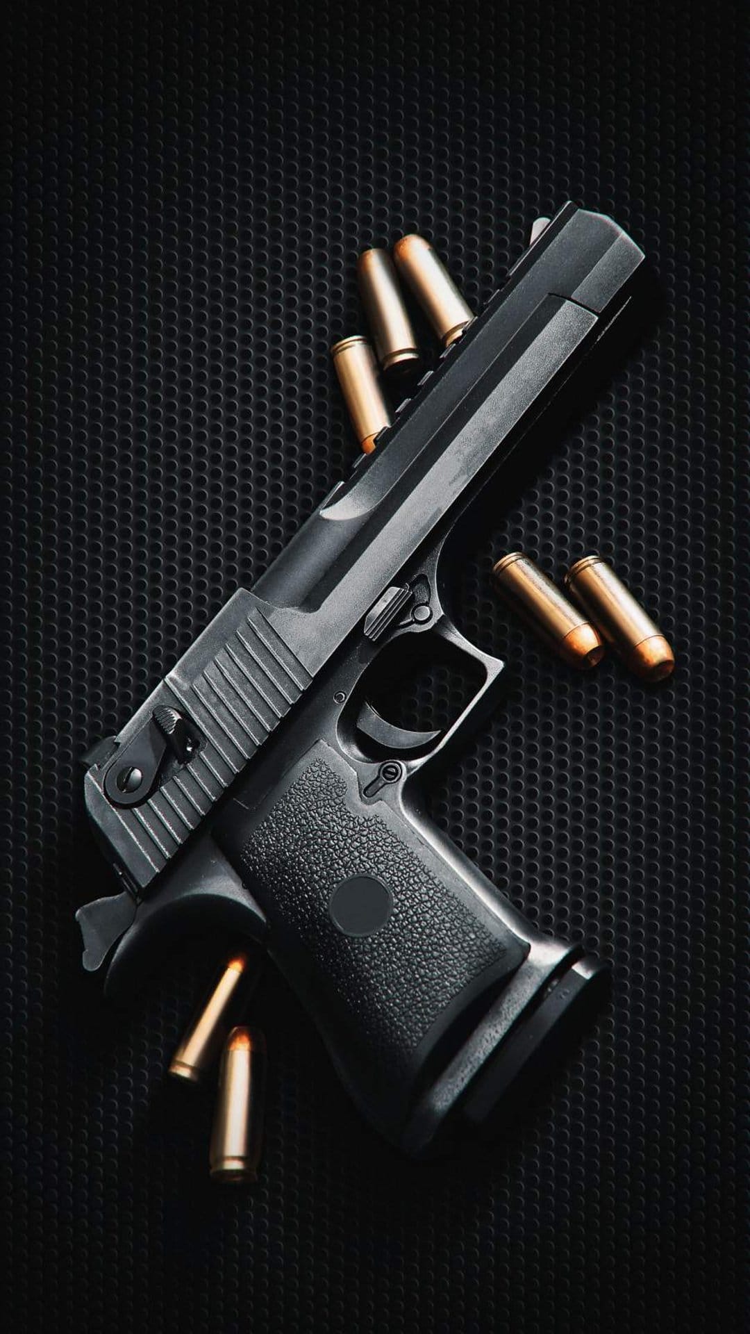 Black semi-automatic pistol surrounded by brass-cased bullets on a dark textured surface in dramatic lighting.