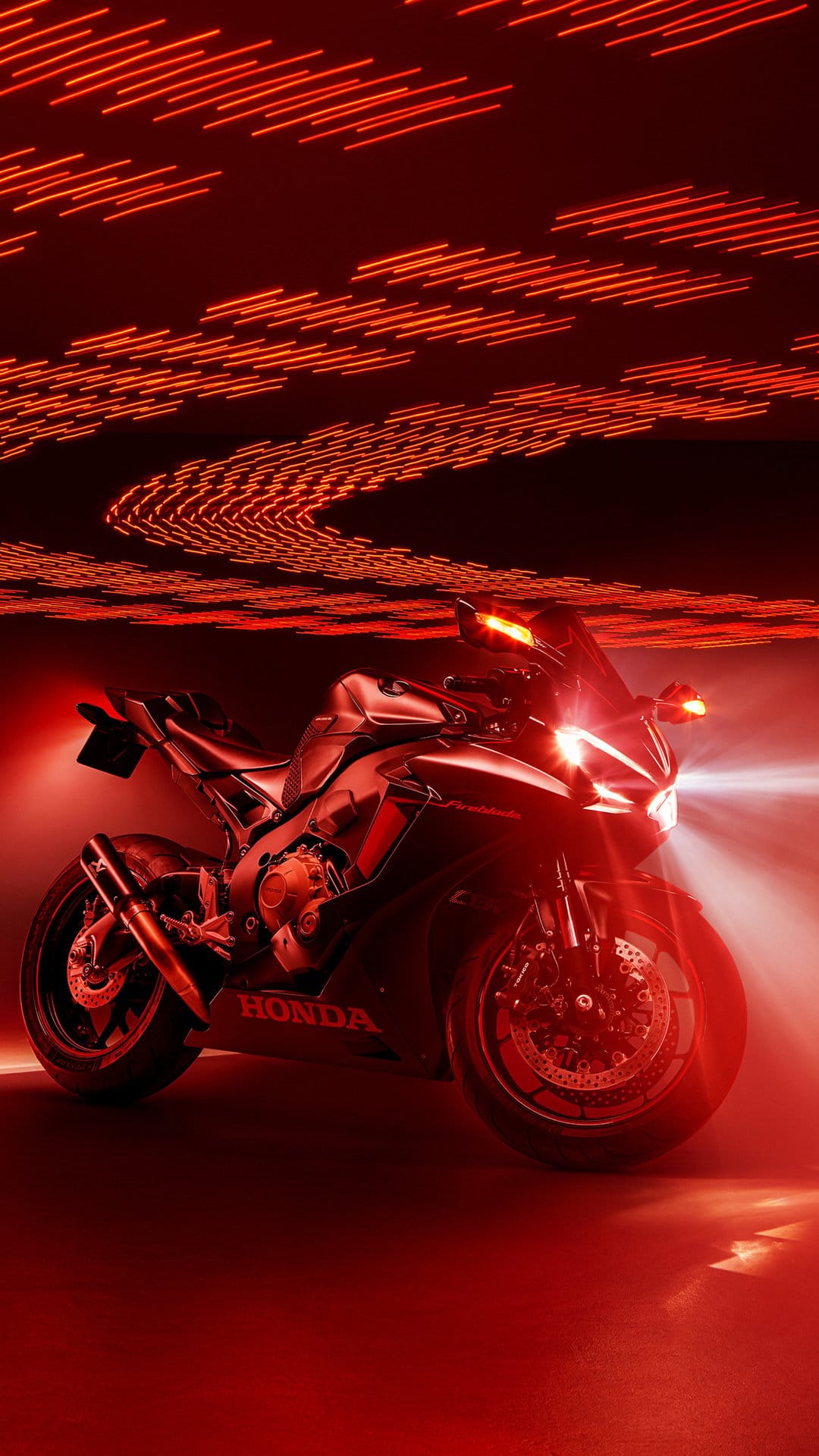 Honda CBR motorcycle illuminated by glowing red neon streaks and bright headlights against a dark night backdrop.