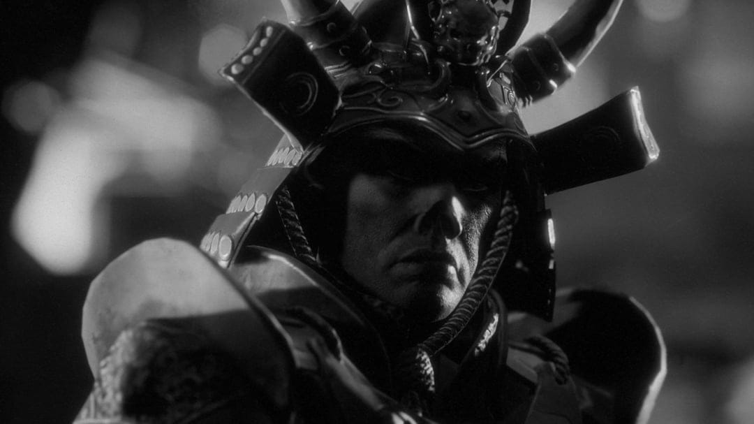 Samurai warrior in detailed horned armor and skull helmet under dramatic high-contrast black and white lighting.