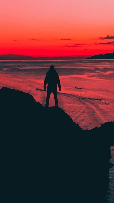 sunset, silhouette, cliff, ocean, dramatic sky, solitude, nature, vibrant colors, contemplation, landscape, red sky, orange hues, peaceful, majestic, serene, adventure, explore, tranquil, horizon, epic