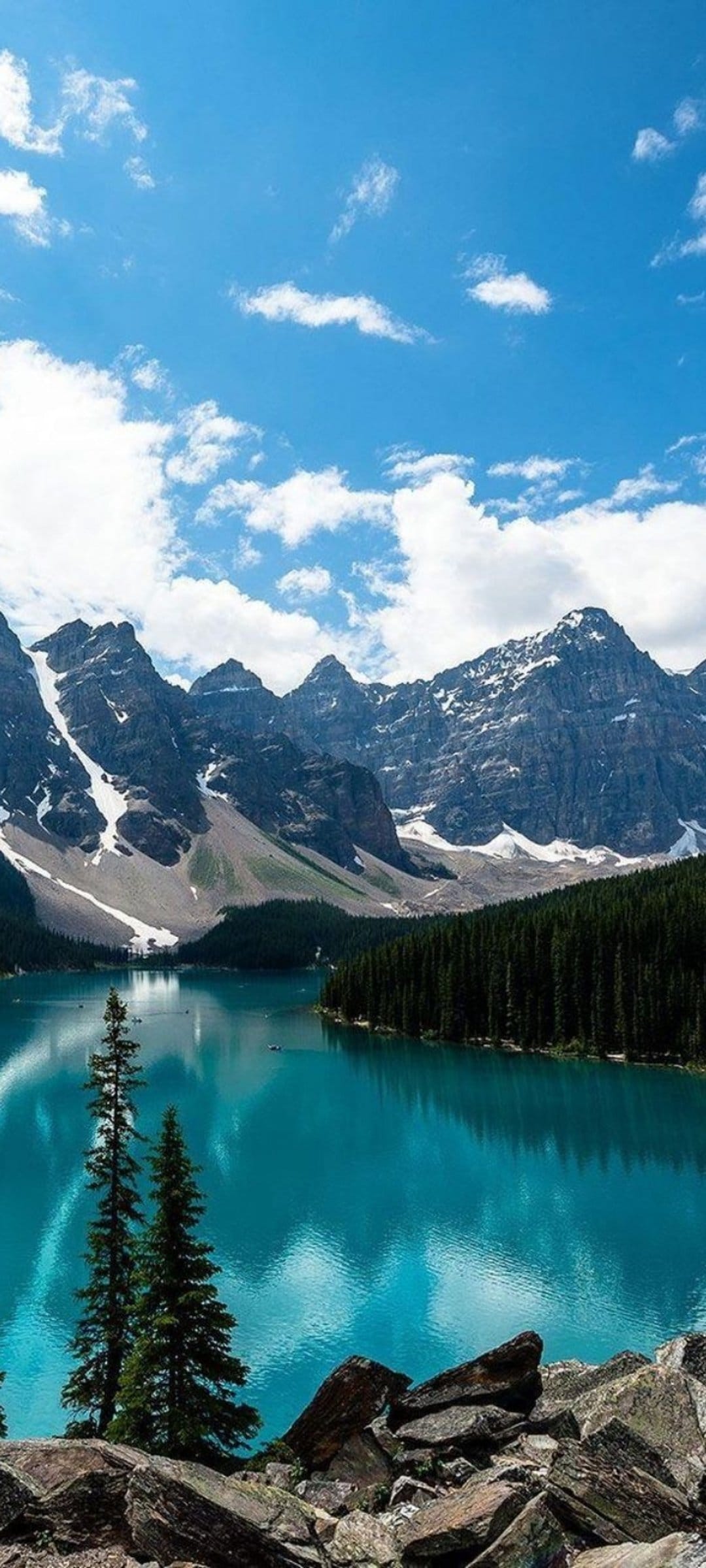 Moraine Lake's turquoise water reflects snow-capped mountains and a pine forest in Banff National Park, Canada.