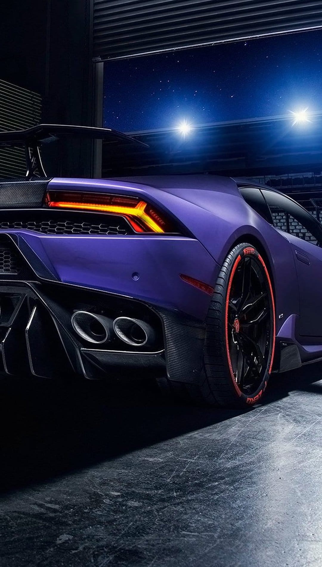 Purple Lamborghini Huracan rear with red LED taillights and black wheels in a garage beneath a starry night sky.