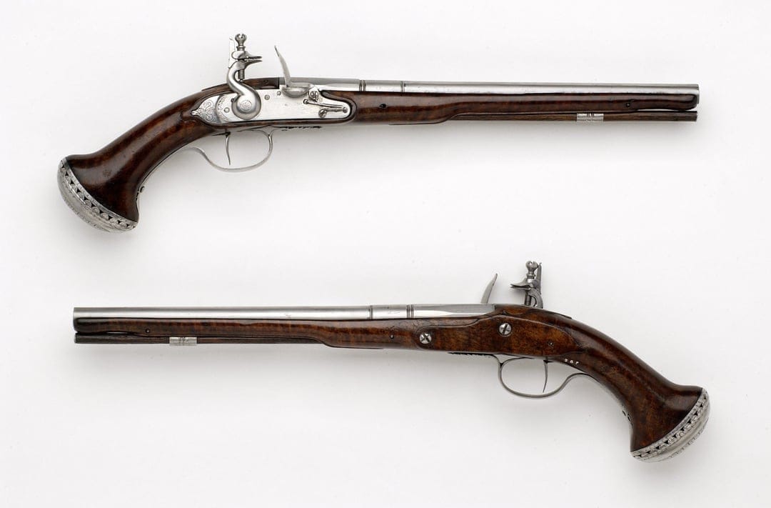 Two antique flintlock pistols with polished wood handles and ornate silver engravings on a dark background.