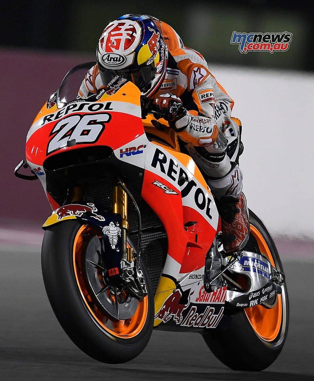 Marc Marquez leaning low on a Repsol Honda RC213V racing motorcycle during a MotoGP turn on a paved track.