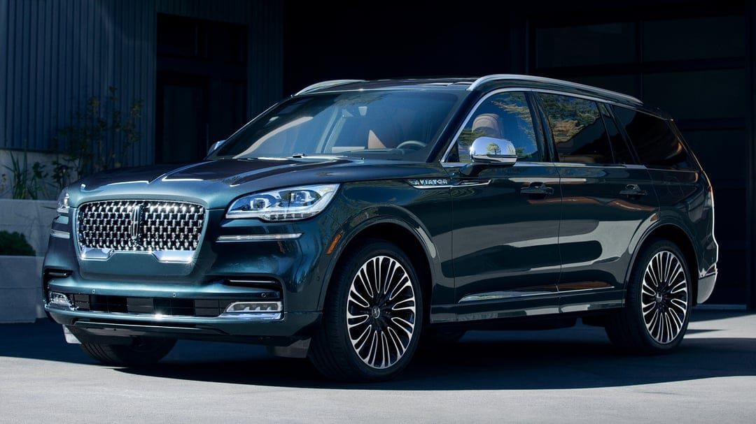 Dark green Lincoln Aviator SUV parked in a modern driveway with chrome accents and multi-spoke wheels.