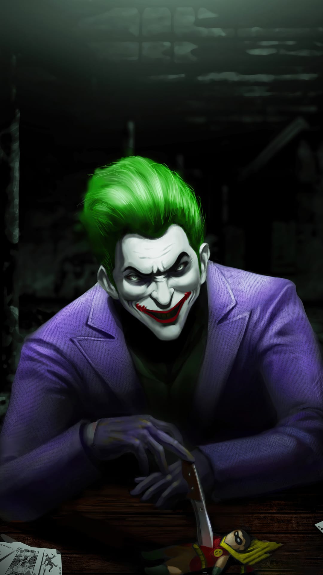 Joker with green hair and purple suit points a knife at a small Robin toy on a dark table with cards.