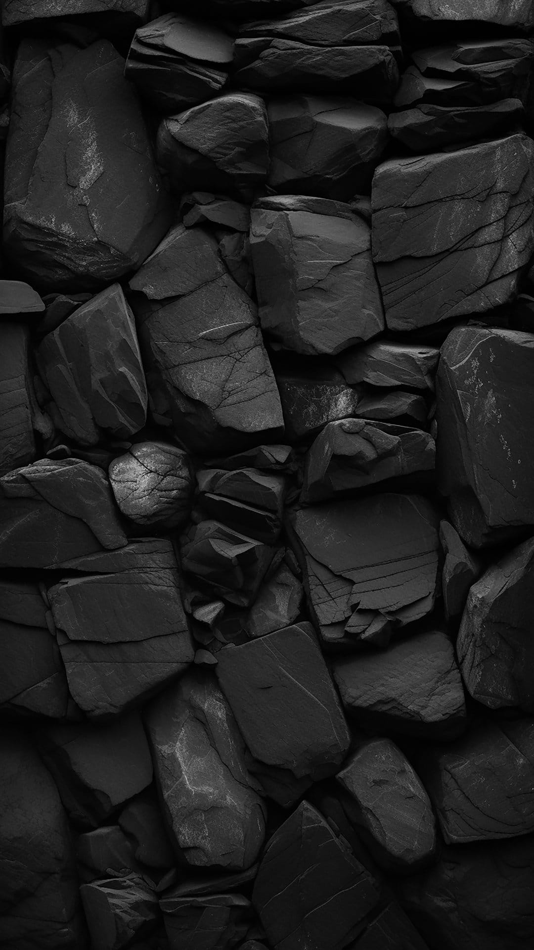 Rough black stone wall with deep cracks, irregular sharp edges, and high-contrast geological surface details.