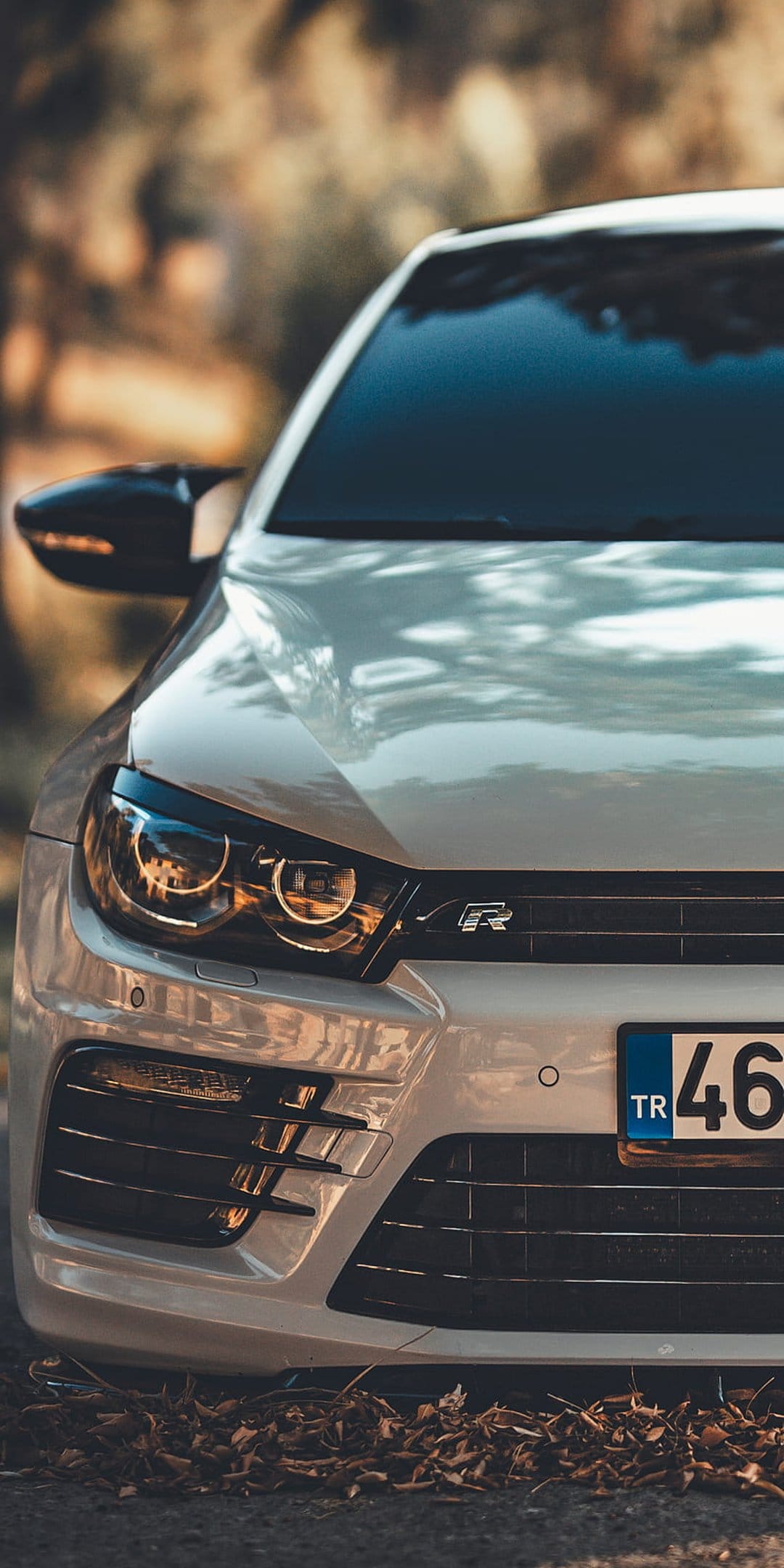 White VW Scirocco R headlight and black honeycomb grille with an R badge under warm natural outdoor light.